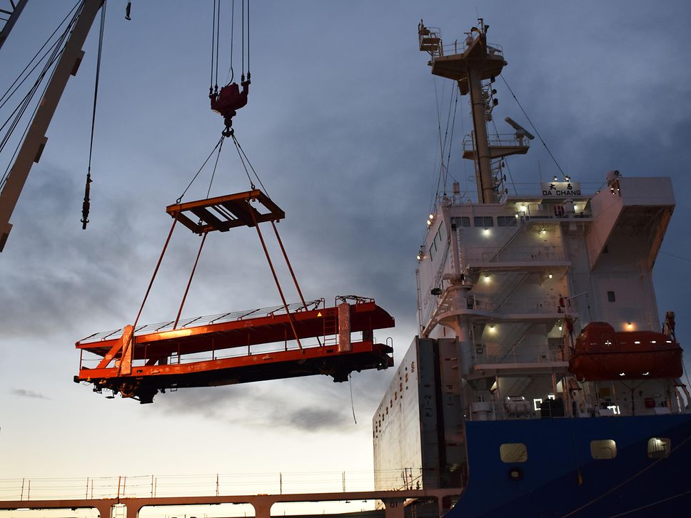 Un camion transporteur de voitures est soulevé d'un navire à l'aide d'une grue.